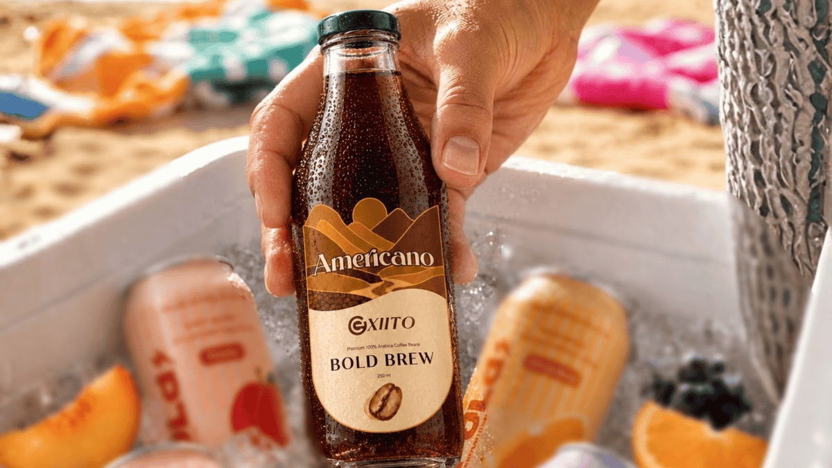 EXIITO Americano Bold Brew bottled coffee chilled on ice at a sunny beach with refreshing summer fruits.